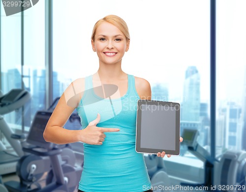 Image of smiling sporty woman showing tablet pc in gym