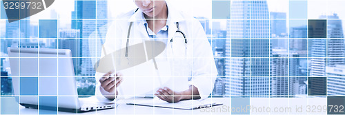 Image of female doctor with laptop pc looking at paper