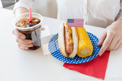 Image of close up of woman eating hot dog with coca cola