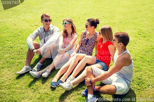 Image of group of smiling friends outdoors sitting in park