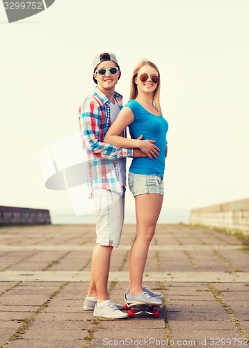 Image of smiling couple with skateboard outdoors