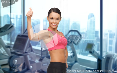 Image of smiling asian woman showing thumbs up over gym