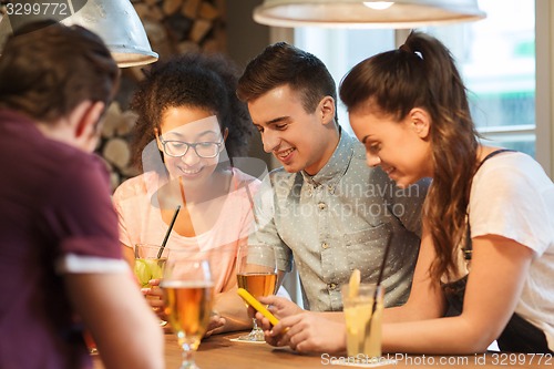 Image of happy friends with smartphones and drinks at bar