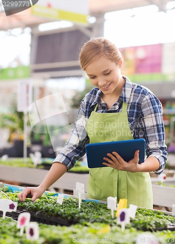 Image of happy woman with tablet pc in greenhouse