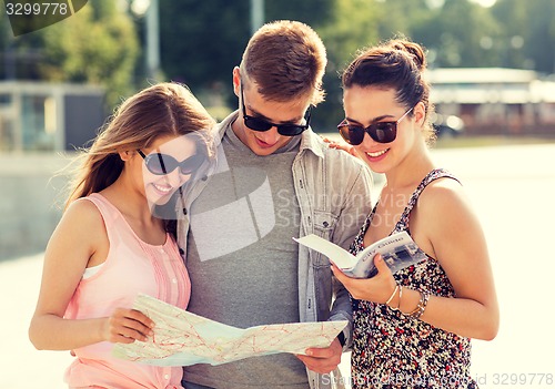 Image of smiling friends with map and city guide outdoors