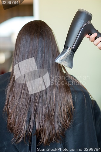 Image of stylist hand with fan dries woman hair at salon