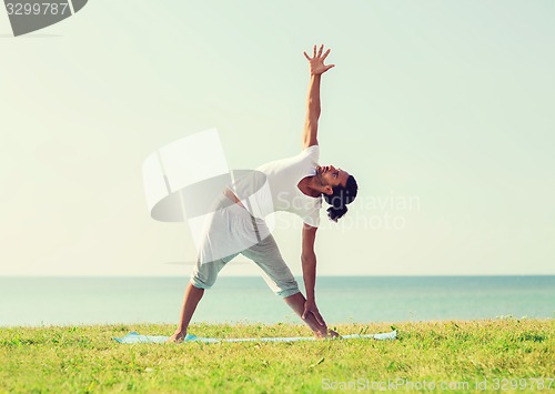 Image of smiling man making yoga exercises outdoors