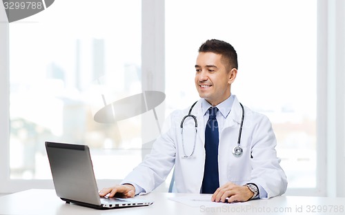 Image of smiling male doctor with laptop in medical office