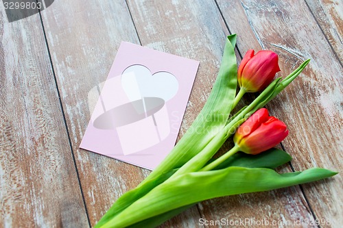 Image of close up of tulips and greeting card with heart