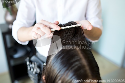 Image of male stylist hands combing wet hair at salon