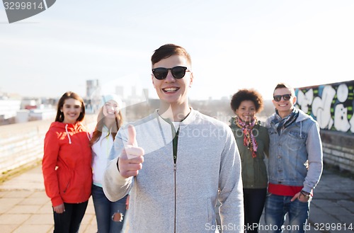 Image of happy teenage friends showing thumbs up on street