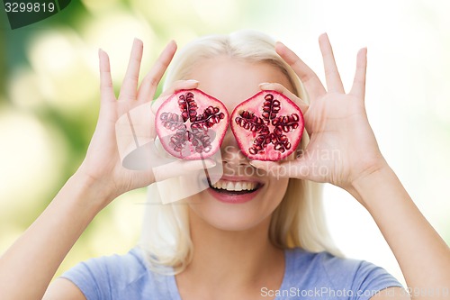 Image of happy woman covering eyes with pomegranate