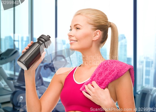 Image of happy woman drinking water from bottle in gym