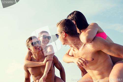 Image of smiling friends in sunglasses on summer beach