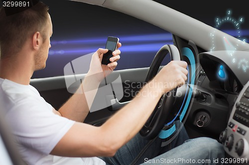 Image of man looking to smart phone while driving car