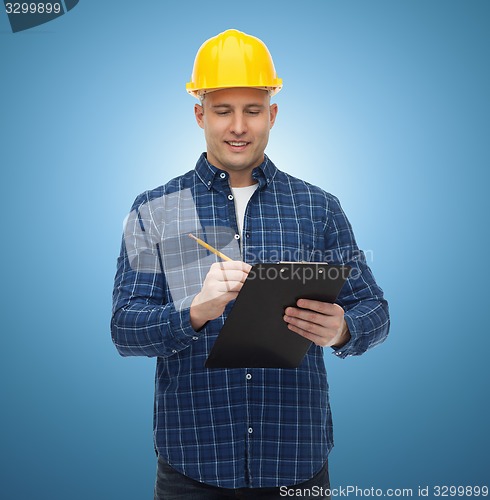 Image of smiling male builder in helmet with clipboard