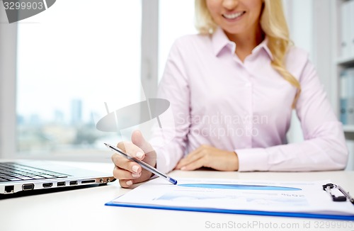 Image of smiling businesswoman reading papers in office