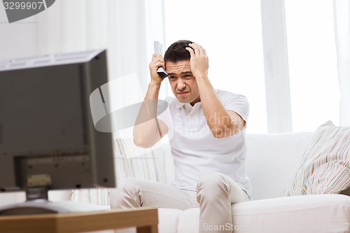 Image of disappointed man watching tv at home