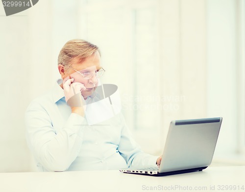 Image of old man in eyeglasses working with laptop at home