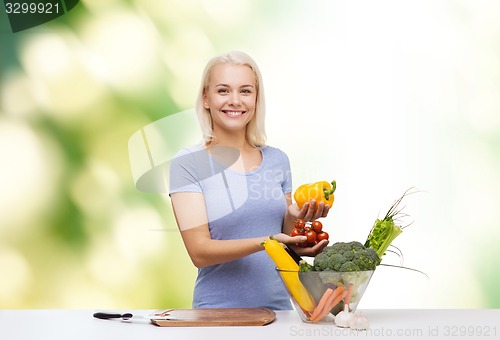 Image of smiling young woman cooking vegetables over green