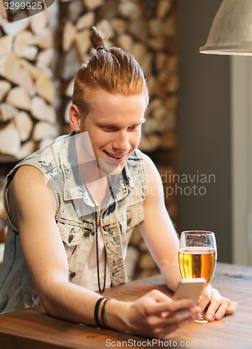 Image of happy man with smartphone drinking beer at bar