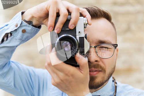 Image of young hipster man with film camera in city