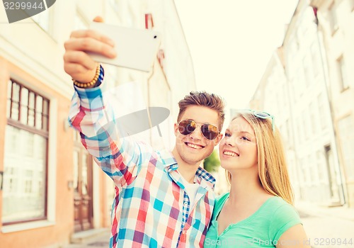 Image of smiling couple with smartphone in city