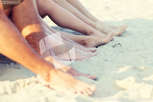 Image of close up of friends sitting on summer beach