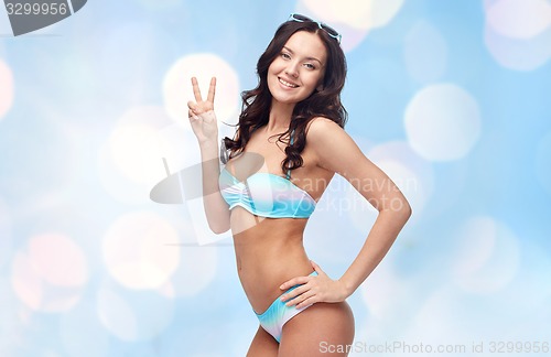 Image of happy woman in swimsuit showing victory hand sign