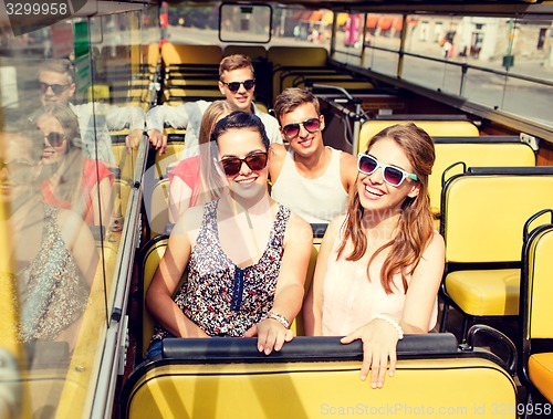 Image of group of smiling friends traveling by tour bus