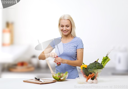 Image of smiling woman cooking vegetable salad on kitchen