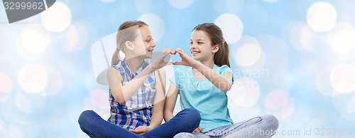 Image of happy little girls showing heart shape hand sign