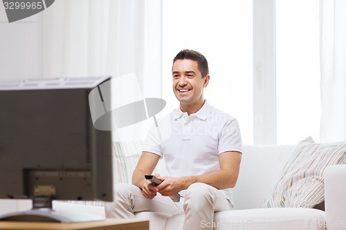 Image of smiling man with remote control watching tv