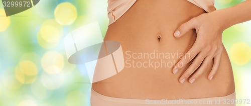 Image of close up of woman pointing finger to bare belly