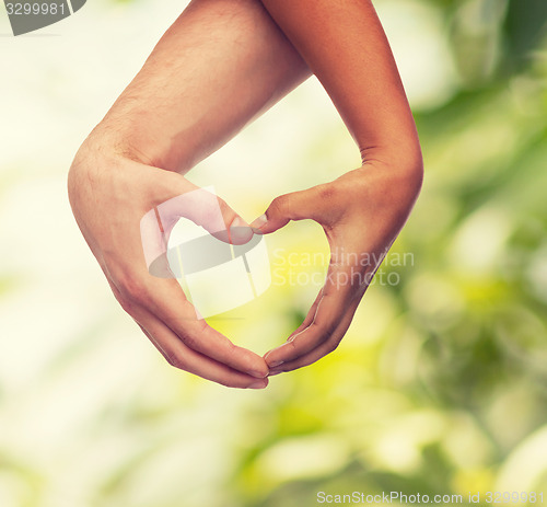 Image of woman and man hands showing heart shape