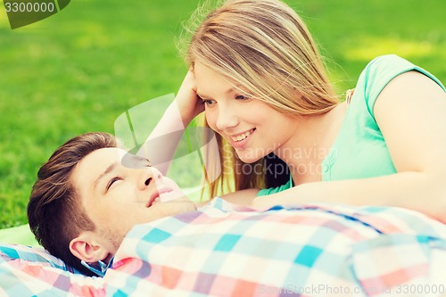 Image of smiling couple lying on blanket in park