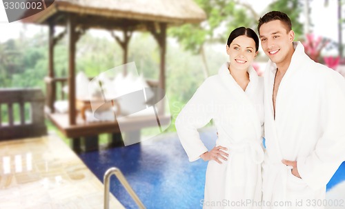 Image of happy couple in bathrobes over spa hotel resort