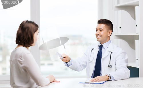 Image of smiling doctor giving pills to woman at hospital