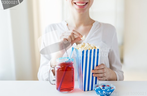 Image of woman eating popcorn with drink in glass mason jar