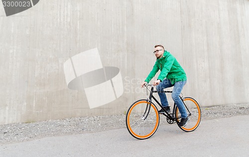 Image of happy young hipster man riding fixed gear bike