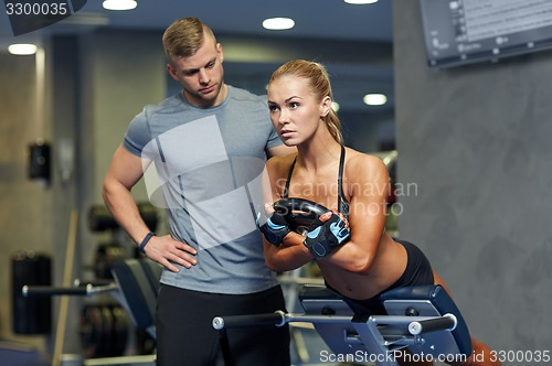 Image of woman with personal trainer flexing muscles in gym