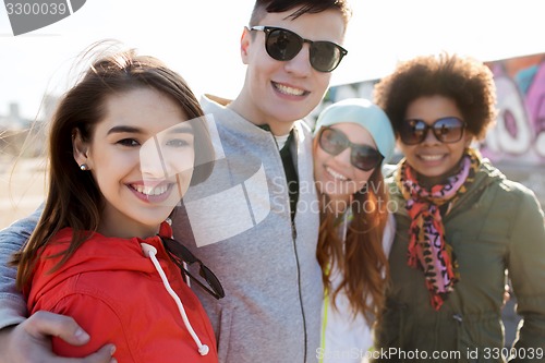 Image of happy teenage friends in shades hugging outdoors