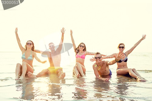 Image of smiling friends in sunglasses on summer beach
