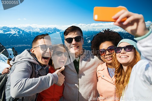 Image of smiling friends taking selfie with smartphone