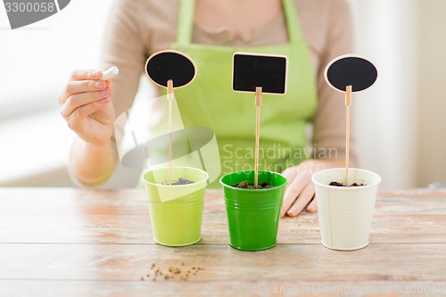 Image of close up of woman over pots with soil and signs