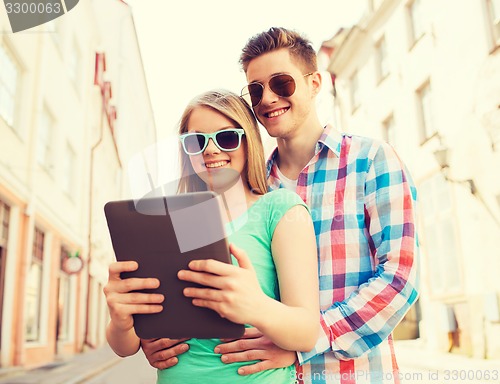 Image of smiling couple with tablet pc in city