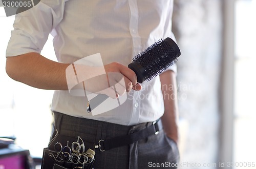 Image of close up of male stylist with brush at salon