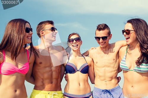 Image of smiling friends in sunglasses on summer beach