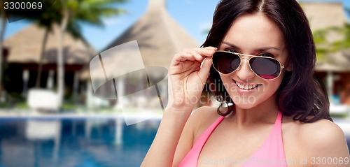 Image of happy woman in sunglasses and swimsuit on beach