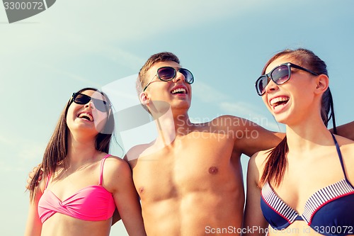 Image of smiling friends in sunglasses on summer beach